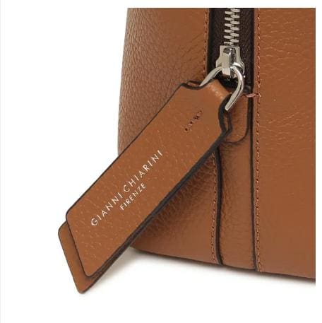 Close-up da bolsa de couro marrom de GIANNI CHIARINI. Tem um zíper de metal e uma etiqueta de couro que diz "GIANNI CHIARINI FIRENZE" em branco. É fabricado na Itália e exala elegância italiana atemporal.