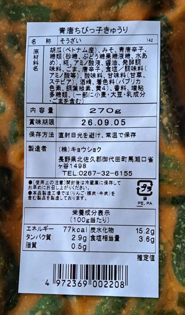 「軽井沢のお土産人気商品 青唐みそ ちびっ子きゅうり 270g 5袋セット」のパッケージに記載されている日本語の食品ラベルには、原材料、栄養成分表示、内容量（270g）、賞味期限（26.09.05）、および保存方法が記載されています。 パッケージの背景には、緑とオレンジ色の漬物、具体的には「チビッ子きゅうり」（ミニキュウリ）が描かれています。この軽井沢の名産品は、「青唐みそ」ならではの本格的な地域の風味を際立たせています。.